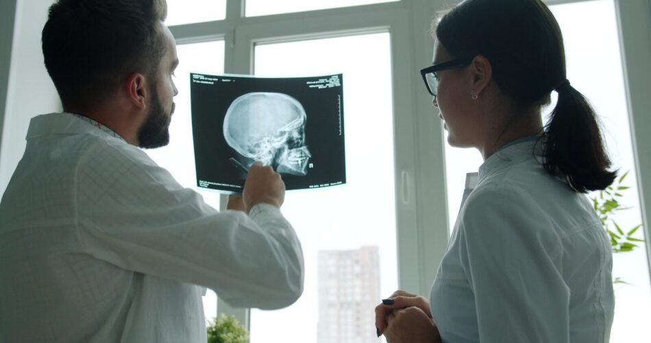 Two doctors examine a skull x-ray together.